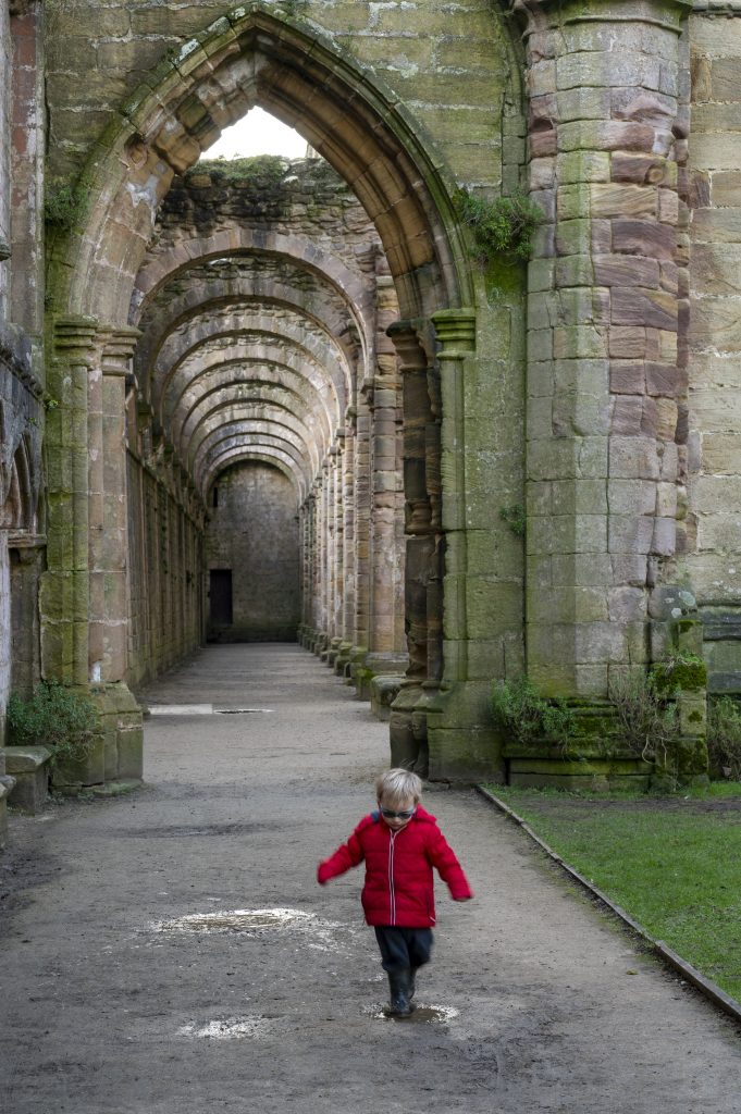 A boy walking through ruined abbey grounds